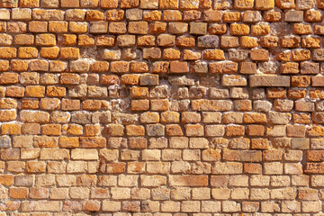 Brick wall in natural red and brown tones, featuring signs of aging and uneven texture. Visible joints and wear add a vintage feel to the surface.