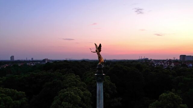 4K Aerial Drone video of a quiet early morning in Munich city center overlooking St Lukas church, Isar river, Marienplatz and the Angel of Peace Friedensengel. Beautiful skyline at a purple sunrise