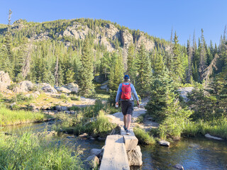 Woman on hiking trail in the mountains; Hiking in Rocky Mountain National Park in Colorado.
