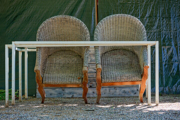 Two vintage wooden chairs leaning on metal barriers outdoors