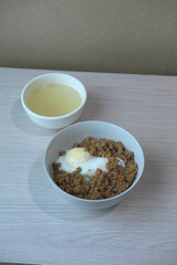A comfort food bowl with minced meat and a half-boiled egg, a simple and nutritious meal. A small bowl of clear soup is visible in the background, completing a classic Asian meal.