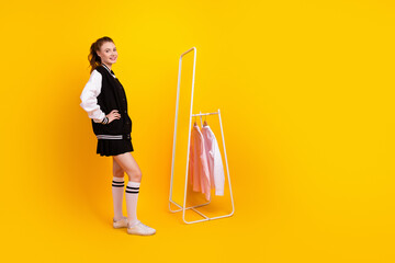 Young girl in stylish casual outfit standing confidently against yellow background with a clothing...