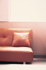 Modern leather sofa with cushion placed near a window in bright interior, minimalistic design concept for living room, home decor, or office lounge space.