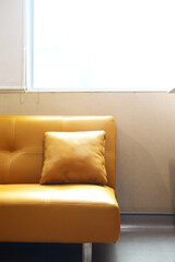 A modern living room with a bright, mustard-yellow sofa serving as a bold centerpiece, complemented by a minimalist interior design and a single decorative cushion.