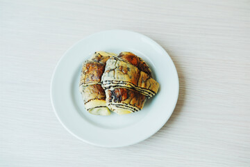 A single piece of sweet bread with a chocolate filling, served on a white plate on a light wood table