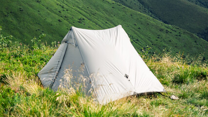 pyramid tent on a mountain pasture on the background of mountains, camping and hiking, hiking in the mountains with tents  © Hordina Anastasia 