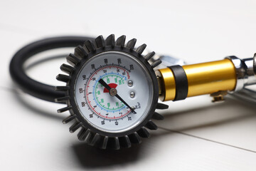 One tire inflation gun with gauge on light wooden table, closeup