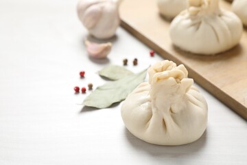 Uncooked khinkalis (dumplings) and spices on white wooden table, closeup. Space for text