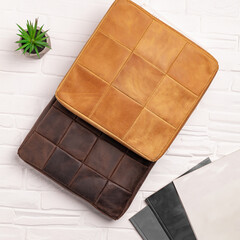 Two leather cushions in a warm brown and tan color scheme are placed on a light textured surface, highlighting their stylish design and comfort for home decor.