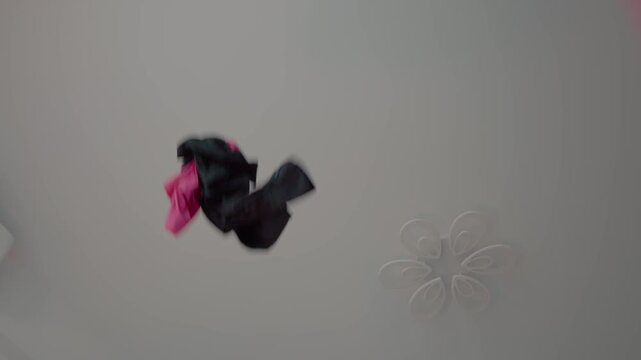 Clothes are scattered all over the living space as they fly around the house, creating a messy scene of disarray and confusion.