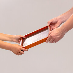 A child and an adult share a moment, passing a wooden box inscribed with DAD. This gesture...