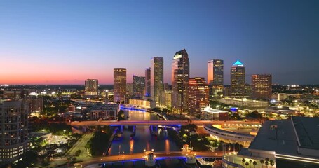 Night urban landscape of downtown district of Tampa in Florida, USA. American city skyline with brightly illuminated high commercial buildings and bridge over Hillsborough river. - Powered by Adobe