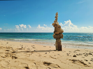 column of coral stones stacked high on a tropical beah forming a sign