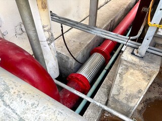 a large red pipe with a stainless steel flexible joint and fittings. The industrial pipe runs along...