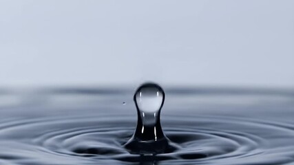 A single water droplet impacts a still surface, creating concentric ripples - Powered by Adobe