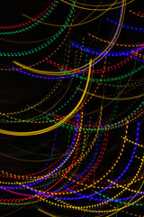 An abstract image with bright, multicolored lines of light on a black background. A long exposure...