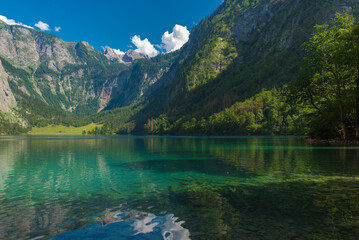 Beautiful Königssee lake in Bavaria, Germany – turquoise alpine water surrounded by majestic mountains and lush forest under clear summer sky.