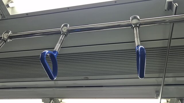 Close-up view of blue subway hand straps hanging inside a modern train interior, symbolizing public transportation and daily commuting.