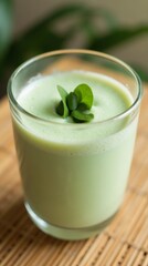Refreshing green smoothie in a glass, garnished with fresh leaves