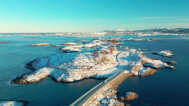 Aerial footage captures the iconic Atlantic Ocean Road Atlanterhavsveien in Norway, transformed by a blanket of snow and ice during winter.