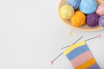 Yellow, green, blue, orange and lilac colors knitting balls in basket with knitting needles and...