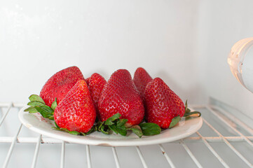 frutillas en la nevera, alimentos dulces a temperatura fría,
fresas frescas en un plato en la...