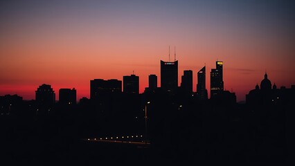 Urban cityscape at twilight with warm glowing windows, simplified silhouette and blurred foreground elements.