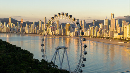 Golden hour view of Balneario Camboriu skyline with the FG Big Wheel ferris wheel at Barra Norte, Santa Catarina, Brazil.