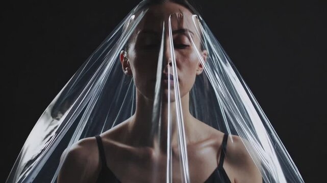 Female individual with synthetic polymer sack fashioned as head covering symbolizing dissent