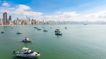 Luxury yachts and boats anchored in front of Balneário Camboriú skyline on a sunny summer day, Santa Catarina, Brazil.