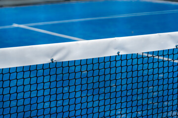 Close-up of net and blue paddle tennis court