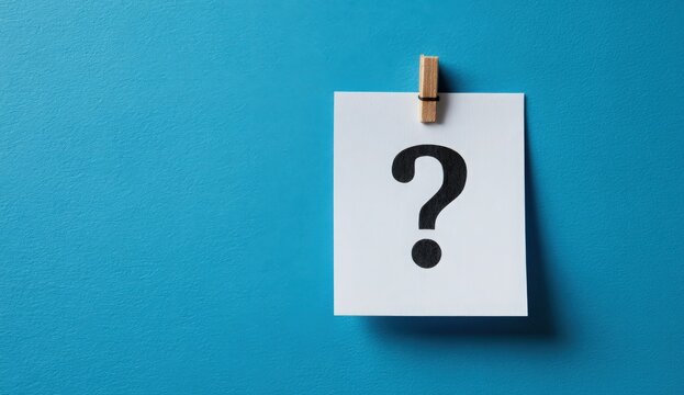 Question Mark on Paper: A striking image featuring a prominent question mark elegantly displayed on a white paper, subtly held in place by a wooden clip, set against a refreshing blue backdrop.