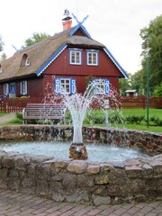 traditional old historic wooden architecture house in Nida, Curonian spit with a fountain in Lithuania, Europe