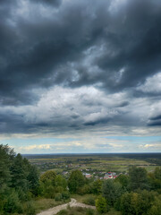 Hilltop view of village under dramatic cloudy sky. Scenic panorama of countryside village before the rain