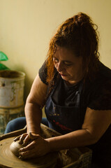 Potter molding clay on pottery wheel creating handicraft in workshop