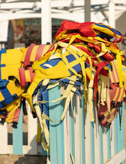 A pile of life jackets are stacked on a fence