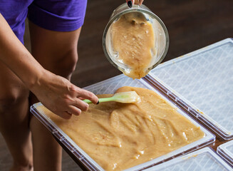 A person is pouring a brown substance into a container