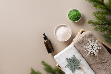 Christmas Spa concept with cosmetic aroma oil, pine cones, evergreen branches on beige background. Winter holiday for body care and wellness. View from above. Special offer for beauty saloon.