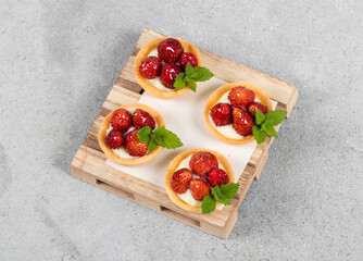 Mini Round Strawberry tartlet. On a wooden board. Light gray background. Top view