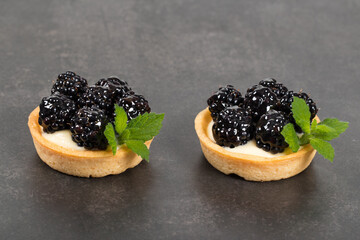 Two Vegan Mini blackberry round tartlets. Dark gray background. Close up