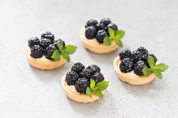 Mini blackberry tartlets. With custard. Light background. Copy space