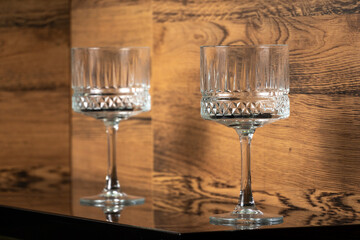 Two champagne glasses on a glass shelf inside a modern wooden kitchen cabinet.