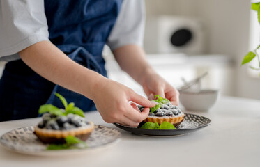 Girl Decorating Blueberry Dessert With Mint Leaves
