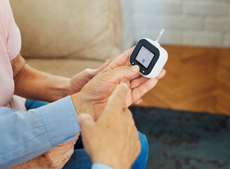 Portrait of senior couple using lancet on finger for checking blood sugar level with glucose meter. Healthcare and medical, diabetes, glycemia concept