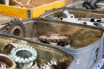 Various motorcycle engine parts, made of metal, steel, or iron. You can see engine blocks, cylinders, sprockets, headlights, speedometers, etc.