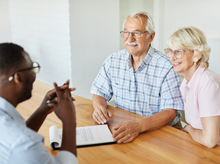 Happy senior old family couple clients make financial insurance estate business deal contract signing, agent lawyer, satisfied mature customers signing contract meeting bank manager agree on investmen