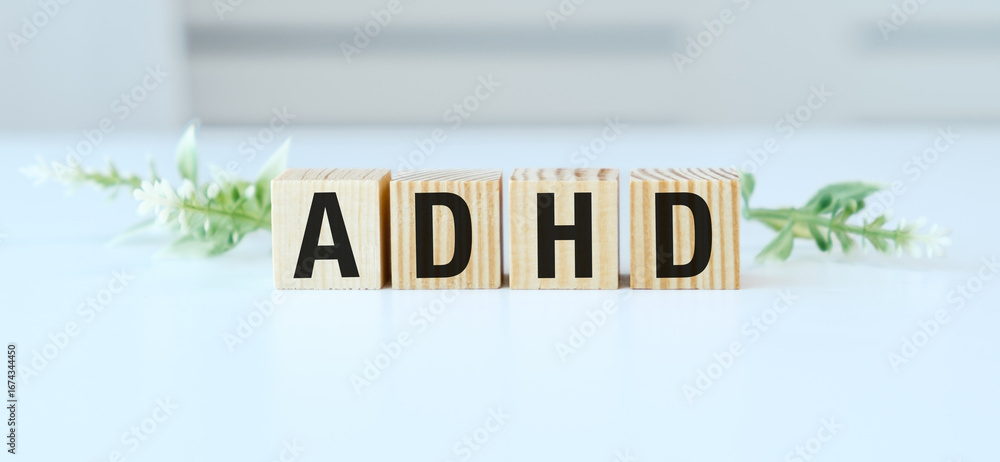 Poster a wooden block with the letters adhd on it. the letters are arranged in a way that they spell out th