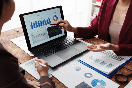 Businesswomen analyzing financial charts and graphs on laptop during meeting