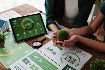Businesswomen holding green moss ball symbolizing environmental conservation during ESG meeting