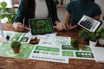 Businesswomen discussing esg and green logistics with solar panel and wind turbine models